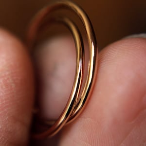 May include: Three gold-colored rings stacked on top of each other. The rings are smooth and shiny.