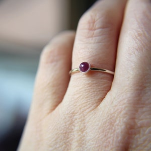 Peut inclure: Une bague en argent avec une petite pierre pr&eacute;cieuse ronde de couleur rose fonc&eacute;.