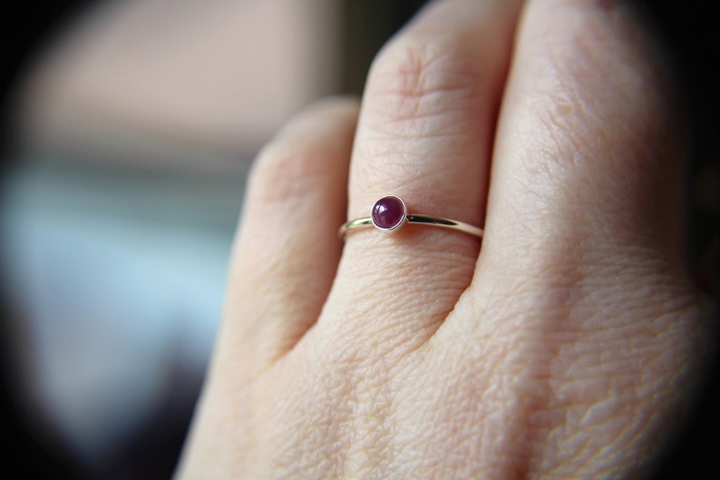 Peut inclure: Une bague en argent avec une petite pierre pr&eacute;cieuse ronde de couleur rose fonc&eacute;.