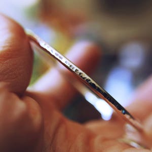 May include: A silver bangle bracelet with a hammered texture.
