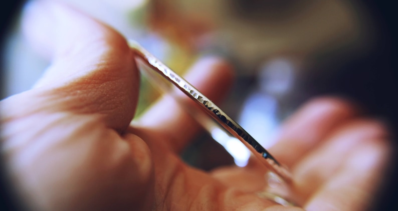 May include: A silver bangle bracelet with a hammered texture.