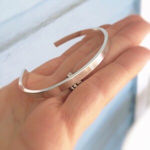 May include: A silver bangle bracelet with a smooth, polished finish.