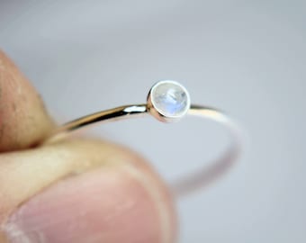 May include: A delicate silver ring with a small, round moonstone.