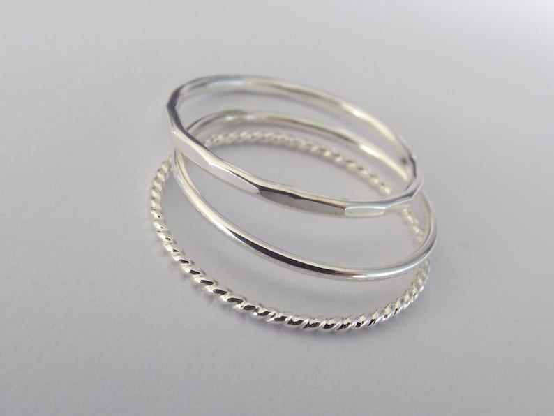K&ouml;nnte beinhalten: Set aus drei silbernen Ringen. Die Ringe sind &uuml;bereinander gestapelt. Der obere Ring ist ein glatter Band, der mittlere Ring ist ein geh&auml;mmertes Band und der untere Ring ist ein gedrehtes Band.