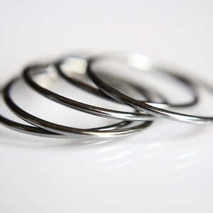 May include: Four silver metal rings stacked on top of each other.