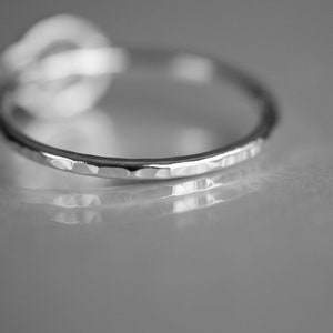 K&ouml;nnte beinhalten: Ein silberner Ring mit geh&auml;mmerter Textur. Der Ring liegt auf einer grauen Oberfl&auml;che.
