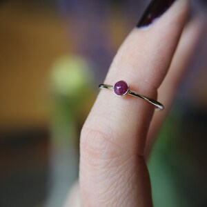 Peut inclure: Une bague en argent avec une petite pierre pr&eacute;cieuse ronde de couleur rouge fonc&eacute;.