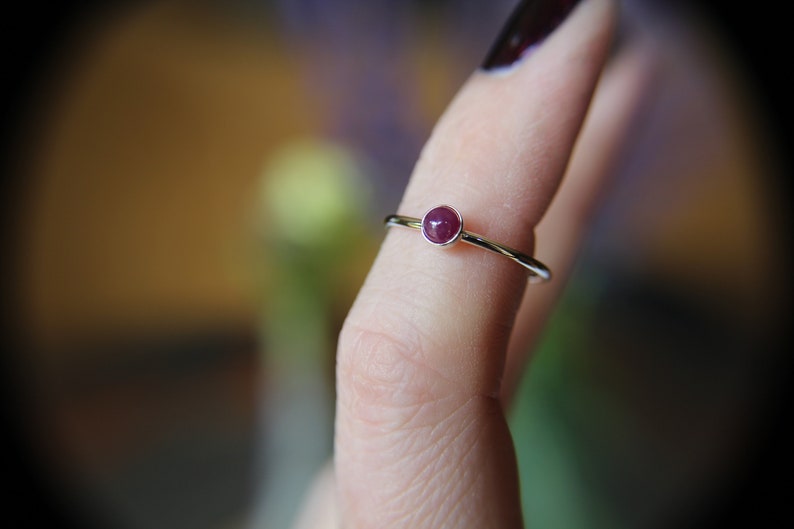 Peut inclure: Une bague en argent avec une petite pierre pr&eacute;cieuse ronde de couleur rouge fonc&eacute;.