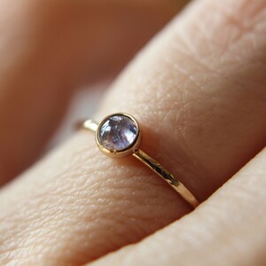 Puede incluir: Un delicado anillo de oro con una banda martillada y una peque&ntilde;a piedra preciosa redonda de color p&uacute;rpura claro.