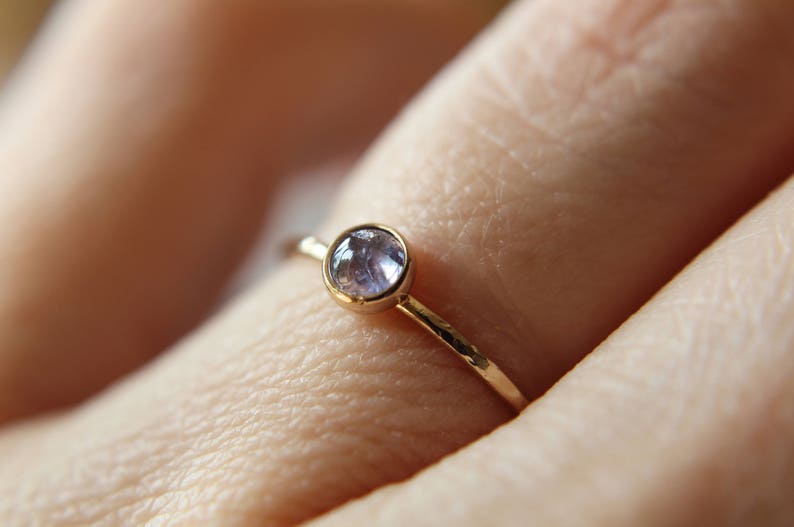Puede incluir: Un delicado anillo de oro con una banda martillada y una peque&ntilde;a piedra preciosa redonda de color p&uacute;rpura claro.