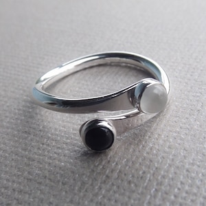 May include: A silver ring with a white and black stone set in a twisted band.