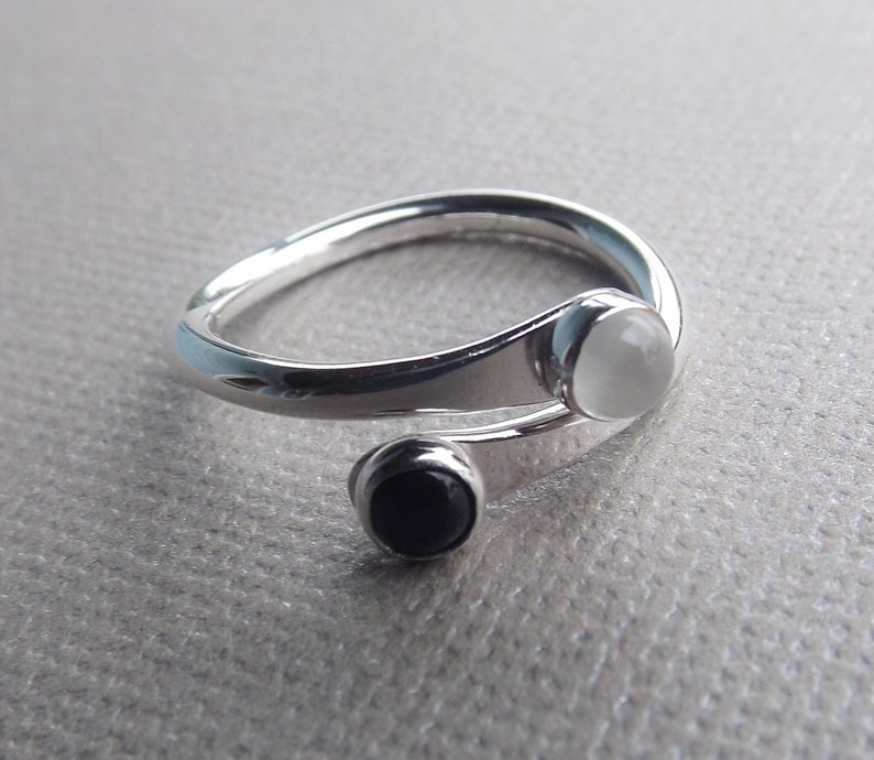 May include: A silver ring with a white and black stone set in a twisted band.
