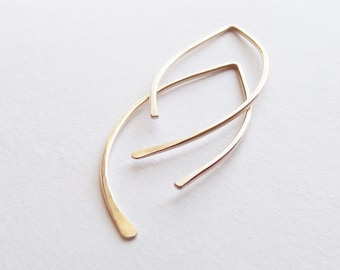 Peut inclure: Une paire de boucles d'oreilles fines en fil de fer de couleur or, dans un style simple et minimaliste. Les boucles d'oreilles ont la forme d'une larme allongée légèrement incurvée.