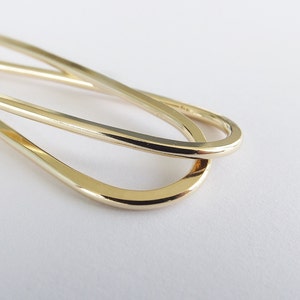 Può includere: Un fermaglio per soldi in metallo dorato con un design semplice ed elegante. Il fermaglio è composto da due anelli intrecciati, creando una curva liscia e continua.