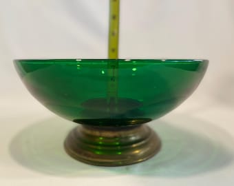 Könnte beinhalten: Eine durchscheinende smaragdgrüne Glasschale mit glattem, abgerundetem Rand, die auf einem kreisförmigen Metallsockel steht. Ein gelbes Maßband ist vertikal im Inneren der Schale positioniert und zeigt eine Tiefe von etwa 6,5 Zentimetern an.