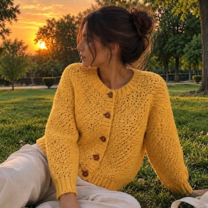 Puede incluir: Un cárdigan de punto amarillo brillante de manga larga con un patrón de textura de punto abierto, cuello redondo acanalado, puños acanalados y dobladillo acanalado. La prenda se abrocha en la parte delantera con cinco botones circulares.