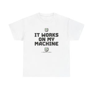 May include: A white short-sleeve t-shirt featuring the black text IT WORKS ON MY MACHINE centered on the chest. Above and below the text are small pixelated computer monitor icons with green checkmarks. Below the bottom icon is the text A DEVELOPER'S MOTTO.