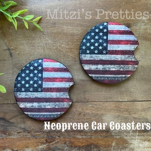 May include: Two round, red, white, and blue American flag car coasters with a distressed look. The coasters are made of neoprene and have a cut-out for a drink.