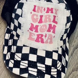 May include: Black and white checkered trucker hat with a pink patch that says "In My Girl Mom Era".