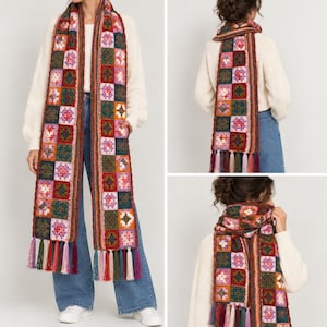 May include: A long crochet scarf featuring a repeating pattern of multicolored granny squares in shades of red, green, pink, and orange. The scarf is finished with long, multi-colored fringe tassels at both ends, creating a textured appearance.