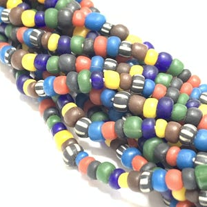 May include: A close-up of a strand of colourful glass beads. The beads are in various shades of blue, green, red, yellow, and brown. Some of the beads have a white stripe pattern.