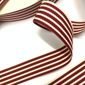 May include: Red and white striped ribbon with a satin finish. The ribbon is approximately 1 inch wide.
