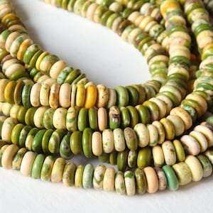 May include: A strand of green, white, and yellow gemstone beads. The beads are round and have a smooth, polished finish.