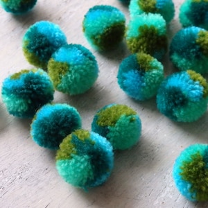 May include: A collection of teal and green pom-poms, resembling miniature fuzzy planets.