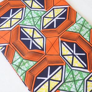 May include: A fabric with a geometric pattern in orange, green, white, and black. The pattern features repeating octagons with a starburst design.