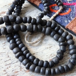 May include: A strand of black glass beads, possibly used for jewelry making or as a prayer mala.