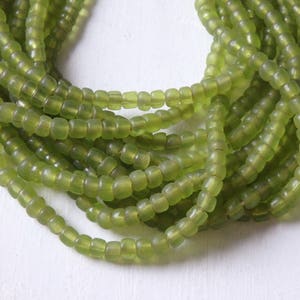 May include: A strand of green glass beads, each bead is slightly rounded and has a matte finish.