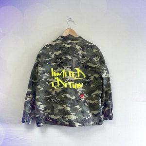 May include: Camouflage jacket with a yellow "limited edition" graphic and star embellishments.