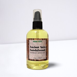 May include: A clear glass bottle with a black pump top and a yellow liquid inside. The bottle is labeled "Herbogen Ancient Aura Sandalwood Scented Body Oil 4 oz | 118 ml".