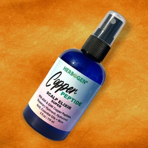 May include: A blue plastic spray bottle containing Herbogen Copper Peptide Scalp Elixir Super. The white label features black text listing ingredients including AHK and GHK Copper Peptides, Rosemary Hydrosol, and Hyaluronic Acid, with 4 fl oz.