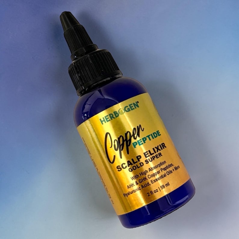 May include: A blue plastic bottle with a black pointed applicator cap and a gold label. The label reads HERBOGEN Copper PEPTIDE SCALP ELIXIR GOLD SUPER With High Absorption AHK & GHK Copper Peptides, Hyaluronic Acid, Essential Oils + More 2 fl oz | 59 ml.