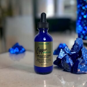 May include: A cobalt blue glass dropper bottle labeled Herbogen Copper Peptide Scalp Elixir Gold Super. The gold label lists ingredients including AHK & GHK Copper Peptides, Rosemary Hydrosol, Hyaluronic Acid, and Essential Oils, with a volume of 2 fl oz.