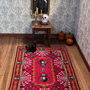 May include: A red and white Halloween-themed rug with a spiderweb design and black spiders. The rug has a gold and black border.