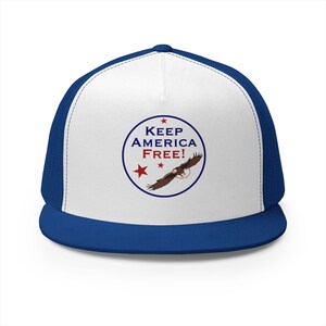 May include: A blue and white trucker hat featuring a circular graphic on the front panel. The design includes the text KEEP AMERICA FREE! in blue and red, accompanied by three red stars and an illustration of a bald eagle in flight.