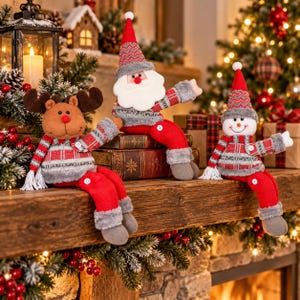 May include: Three plush Christmas shelf sitters featuring a reindeer, Santa Claus, and a snowman. Each figure wears a red and gray patterned sweater, a matching hat, and red pants with white buttons. They have soft gray boots and white fringe accents.
