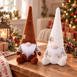 May include: Two plush gnome figurines sitting side by side. The left gnome has a tall brown textured hat with a gold star, brown body, and white beard. The right gnome has a tall white knit hat with a gold star, white body, and white beard.