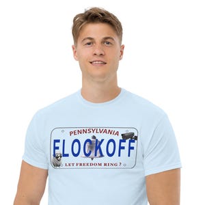 Puede incluir: Una camiseta azul claro con un gráfico de una matrícula de Pensilvania. La placa muestra el texto "FLOCKOFF" en azul, "PENNSYLVANIA" en la parte superior y "LET FREEDOM RING?" en la parte inferior, con iconos de una oveja, una campana y una cámara.