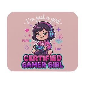 May include: A rectangular mouse pad with a light pink background featuring a cartoon character wearing headphones and a pink hoodie, holding a game controller. Text reads I'm just a girl, PLAY, 1up, and CERTIFIED GAMER GIRL.