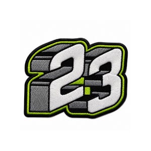 May include: An embroidered patch featuring the number 23 in a bold, white, three-dimensional font. The design includes grey and black block-like shading with a vibrant lime green outline, all bordered by a thick black stitched edge.