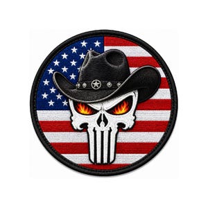 May include: A circular embroidered patch featuring a white skull with fiery orange and yellow eyes, wearing a black cowboy hat with a silver star band, set against a background of the American flag with red, white, and blue stripes.