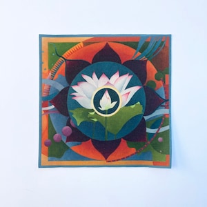 May include: A square canvas print with a colorful mandala design featuring a white lotus flower in the center. The mandala is surrounded by concentric circles of orange, purple, blue, and green.