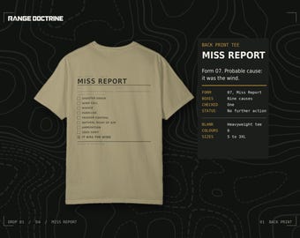 May include: A tan short-sleeved t-shirt featuring a black graphic on the back that resembles a form titled MISS REPORT. The design includes a checklist with options like SHOOTER ERROR, WIND CALL, and a checked box for IT WAS THE WIND.