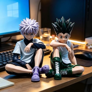 May include: Two anime character figures sitting side by side. The left figure has spiky light purple hair, a white short-sleeved shirt over a dark long-sleeved top, dark shorts, and purple sneakers. The right figure has spiky black hair, a white tank top, dark green shorts, and dark green boots.
