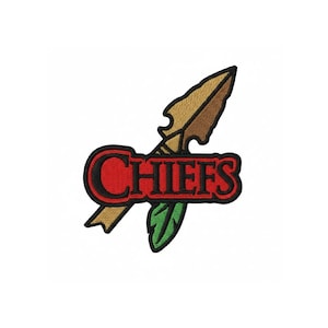 May include: An embroidered patch featuring a tan and brown arrowhead shape positioned behind a red banner with a black border. The word CHIEFS is stitched in black letters across the red banner. A green feather is visible below the banner.