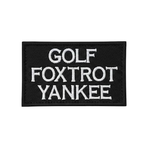 May include: A rectangular black embroidered patch with a stitched border. The text GOLF FOXTROT YANKEE is embroidered in white capital letters across three lines, centered on the black fabric background with a visible textured thread finish.