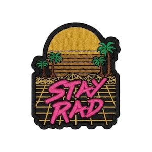 Puede incluir: Un parche bordado que muestra un sol amarillo poniéndose sobre un horizonte con palmeras verdes. El primer plano presenta un patrón de cuadrícula amarilla sobre fondo negro con el texto STAY RAD bordado en letras rosas brillantes.